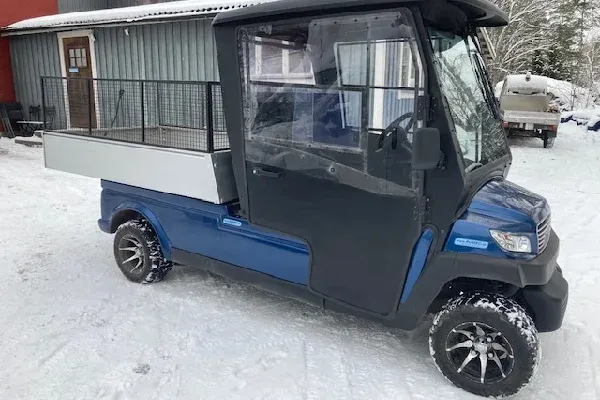 Blått elfordon med hytt och flak i snö