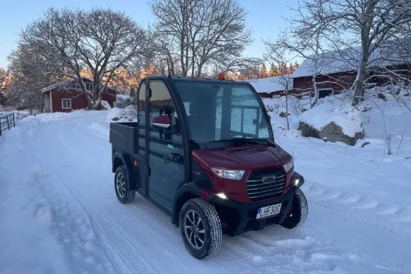 Elfordon med svart hytt, röd front och flak, på en snöig väg